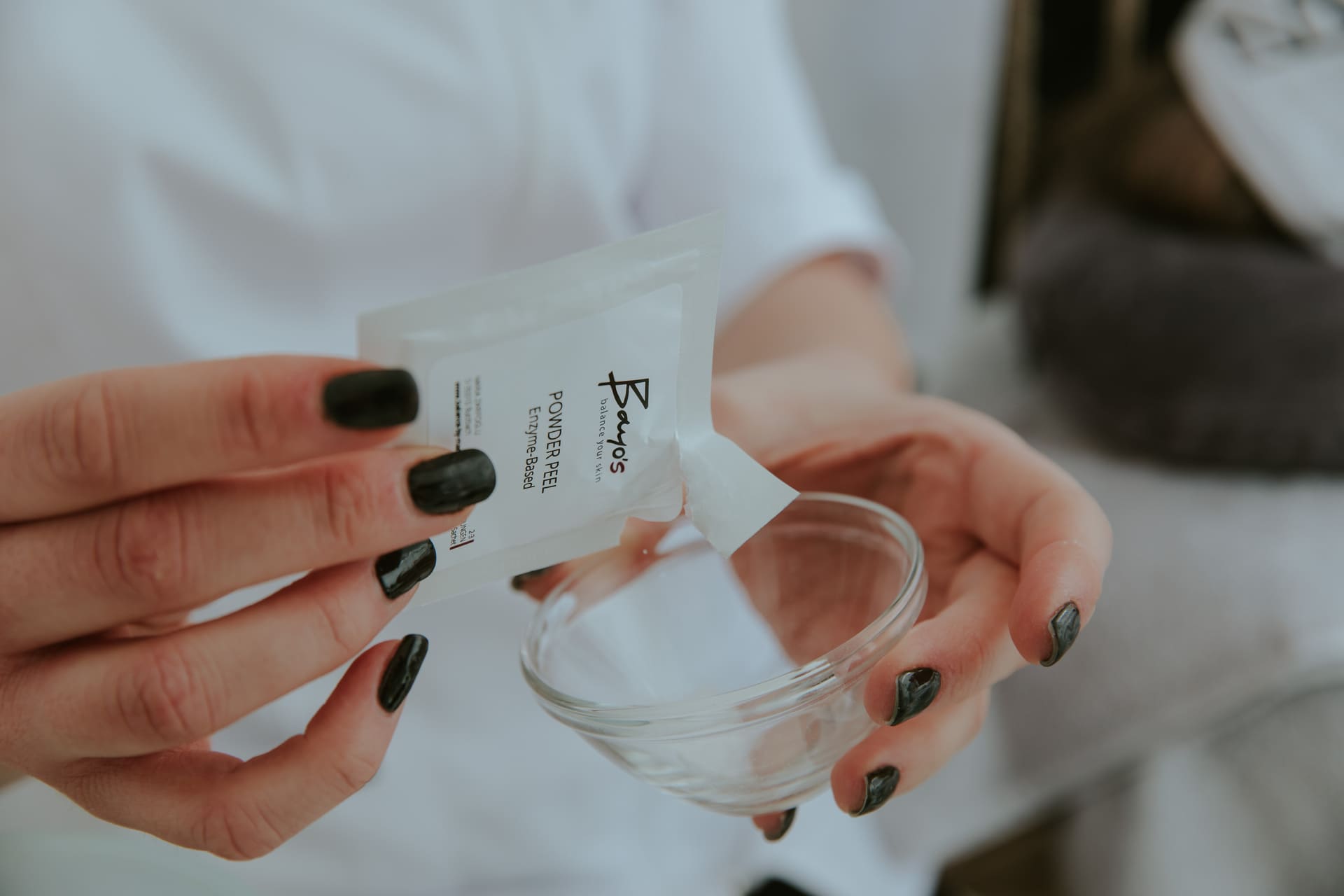 Eine Frau in Marias Kosmetikinstitut hält zum Ausgleich eine Packung Gesichtsmaske in einem Glas.