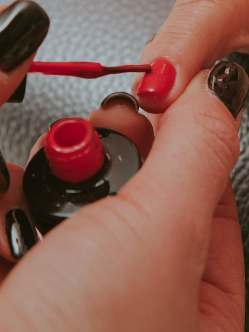 Eine Frau lässt sich in einem Kosmetikinstitut die Nägel mit roten und schwarzen Nägeln machen.