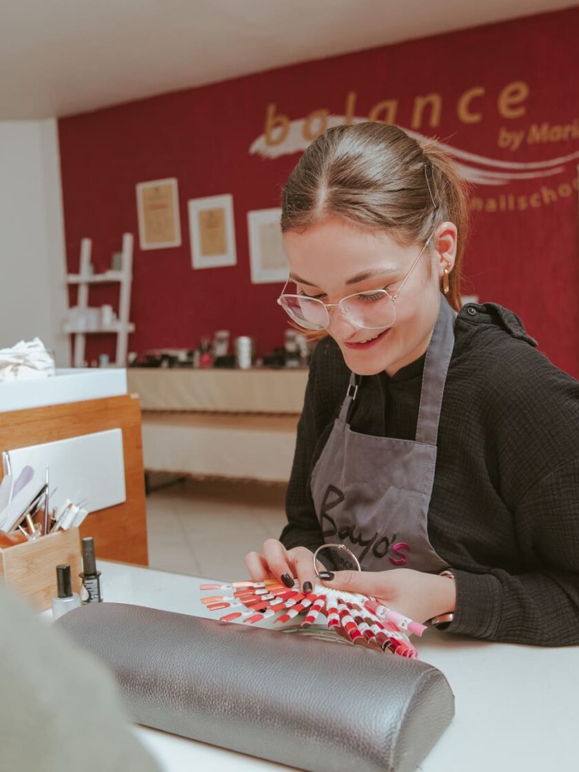 Eine Frau lässt sich an einem Tisch in einem Schönheitssalon eine Maniküre gönnen.