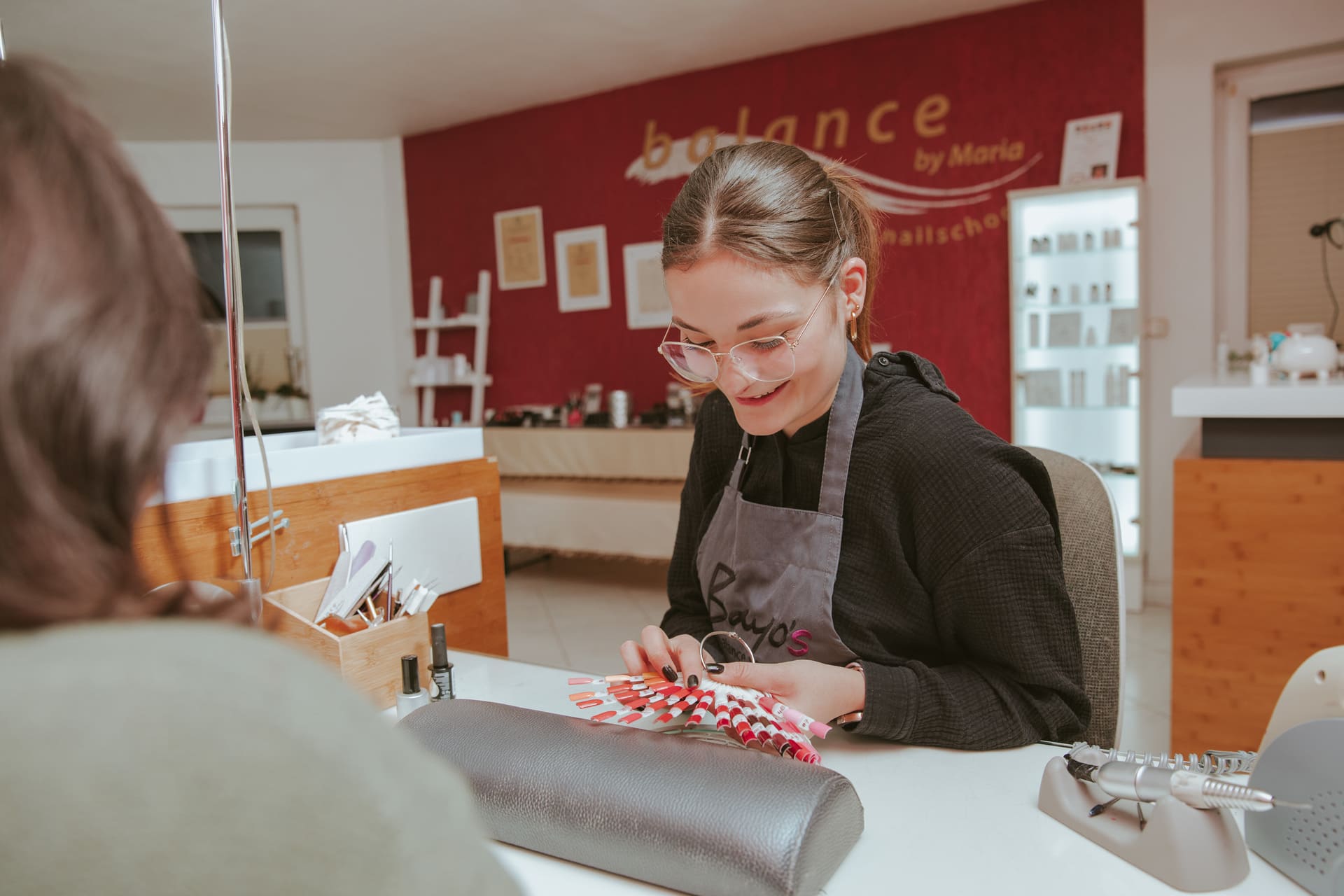 Eine Frau lässt sich an einem Tisch in einem Schönheitssalon eine Maniküre gönnen.